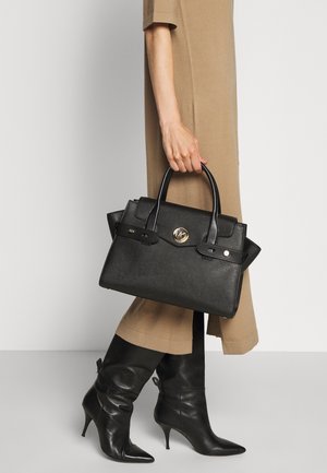 Sac à main structuré noir avec une surface texturée, doté de deux poignées supérieures, d'un logo doré et d'accents métalliques noirs.