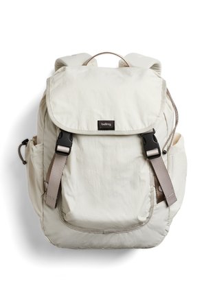 Zaino Bellroy color crema con copertura a patta, due cinturini frontali con fibbie, tasche laterali, spallacci imbottiti e manico superiore.