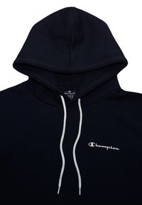 Marinblå huvtröja med framficka, vita snören och en liten vit "Champion"-logga på bröstet. Mjuk tygstruktur.