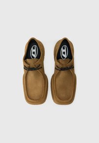 Καφέ σουέτ παπούτσια με στρογγυλερή μύτη και ραμμένες λεπτομέρειες. Ελαστική σόλα με υφή για καλύτερη πρόσφυση. Μαύρα κορδόνια με πορτοκαλί λεπτομέρειες.