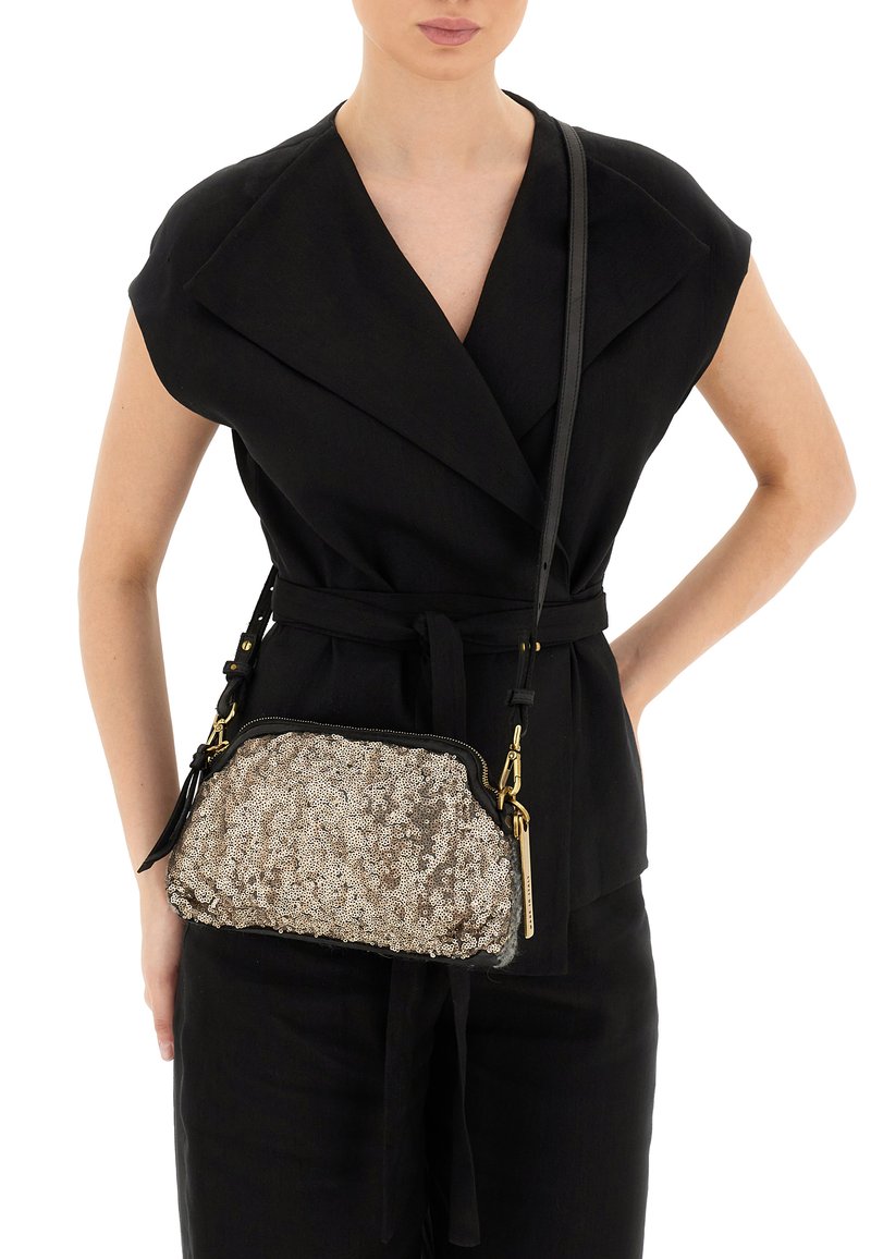 Clutch bag in paillettes ovali dorati e argentati con bordatura nera, chiusura con zip superiore e tracolla regolabile, indossato a bandoliera su un outfit nero.