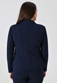 Marineblauwe op maat gemaakte blazer met een gestructureerde kraag, lange mouwen, een getailleerde silhoutte en een peplum zoom, gemaakt van een soepele stof.