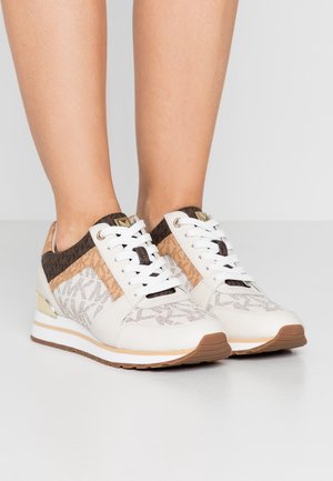 Baskets blanches avec une tige en textile à motif, des accents marron, des détails en liège et un talon compensé léger. Comprend des lacets blancs et une semelle texturée.