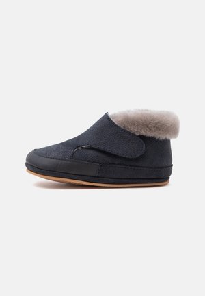Chausson d’hiver bleu foncé avec doublure en fourrure grise douce, fermeture par bride velcro, semelle noire et semelle extérieure en caoutchouc marron, vu de côté gauche.