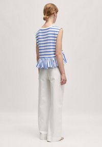 Gestreepte blauw-witte peplumtop met mouwloos ontwerp, met een rucheszoom. Gepaard met wijde witte broek.
