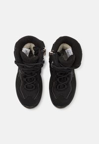 Black sneakers with a textured fabric upper, padded collar, and rubber sole. Features laces and zippers for secure fit.