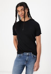 Black short-sleeve t-shirt with a crew neckline and subtle logo accent, paired with light blue denim jeans featuring a classic fit.