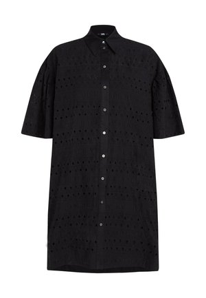 Robe chemise noire surdimensionnée avec un col pointu, des manches courtes, et un motif texturé comportant des découpes et des lettres en relief. Fermeture à boutons sur le devant.