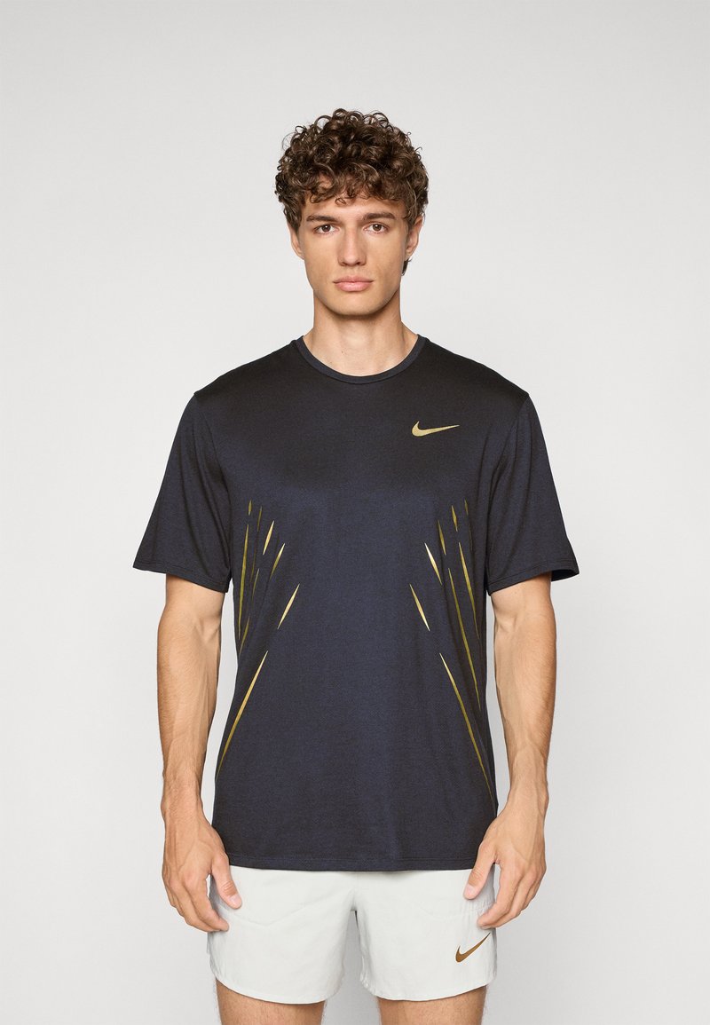Námořnická modrá pánská krátká tričko Nike s zlatými diagonálními akcenty a kulatým výstřihem. Měkká tkanina s mírným leskem.