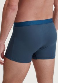 Donkerblauwe herenboxershorts met een blauwe tailleband waarop de merknaam "CALIDA" is geperst. Zacht materiaal en een aansluitend ontwerp.
