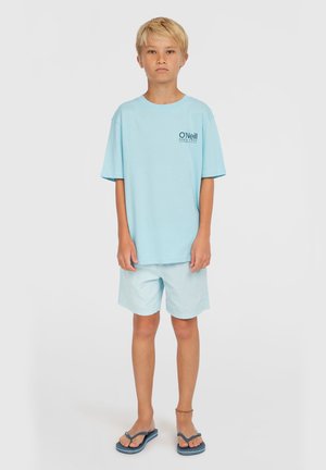 Ljusblå t-shirt med kort ärm och logotyp på bröstet, i kombination med matchande ljusblå shorts och blåa flip-flops. Enkel, avslappnad design.