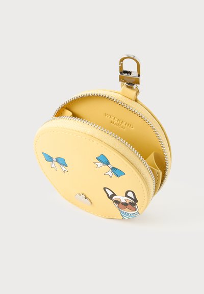 Porte-monnaie rond jaune avec fermeture éclair argentée, nœuds bleus et illustration d'un chien portant des lunettes de soleil et une écharpe.