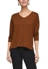 Brun stickad tröja med V-ringning, långa ärmar och en lös passform. Har ribbade muddar och en något längre bakre fåll.