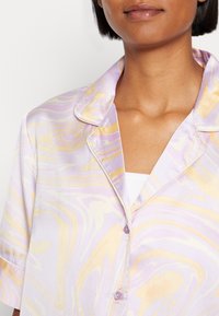 Lavendel- och guldfärgad marmorering på silkespyjamasöverdel med slagkrage, korta ärmar och knapplist framtill.