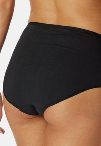 Sort højtaljet undertøj der fremviser glat, strækbart stof med et sømløst design og en mellemhøj benudskæring. Ingen synlige dekorationer.