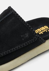 Scarpe slip-on Clarks Originals in suede nero con cuciture a vista e suola in crepe bianco sporco, con logo impresso sul lato.