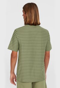 Green striped short-sleeve t-shirt with a crew neck and a relaxed fit. Fabric has a smooth texture, with a small logo on the side seam.