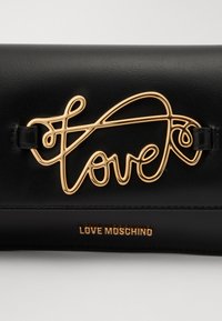 Borsa in pelle nera con un logo "love" in tonalità oro come elemento di design principale e branding impresso nella parte inferiore.