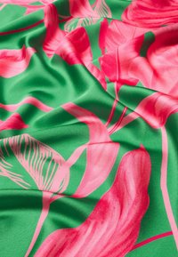 Satinlignende stof med en grøn baggrund, der har store pink blomster mønstre og subtile bladdesigns, hvilket skaber et livligt, tekstureret udseende.