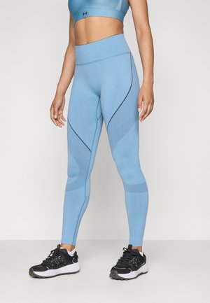 Heledad sinine spordileggings, millel on tekstuuriga mustrid ja mustad aksessuaarid, kõrge vöökoht ja keha lähedane lõige.
