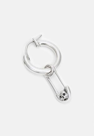 Boucle d'oreille en argent en forme d'anneau avec un pendentif épingle de sûreté orné d'un petit motif de crâne sur le fermoir de l'épingle.