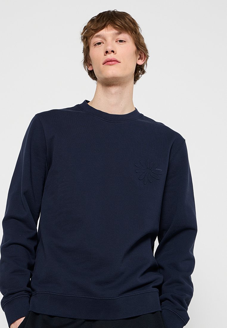 Marineblauwe sweatshirt van zachte stof, met een ronde halslijn, geribbelde manchetten en een gestructureerd bloemdesign op de linkerborst.