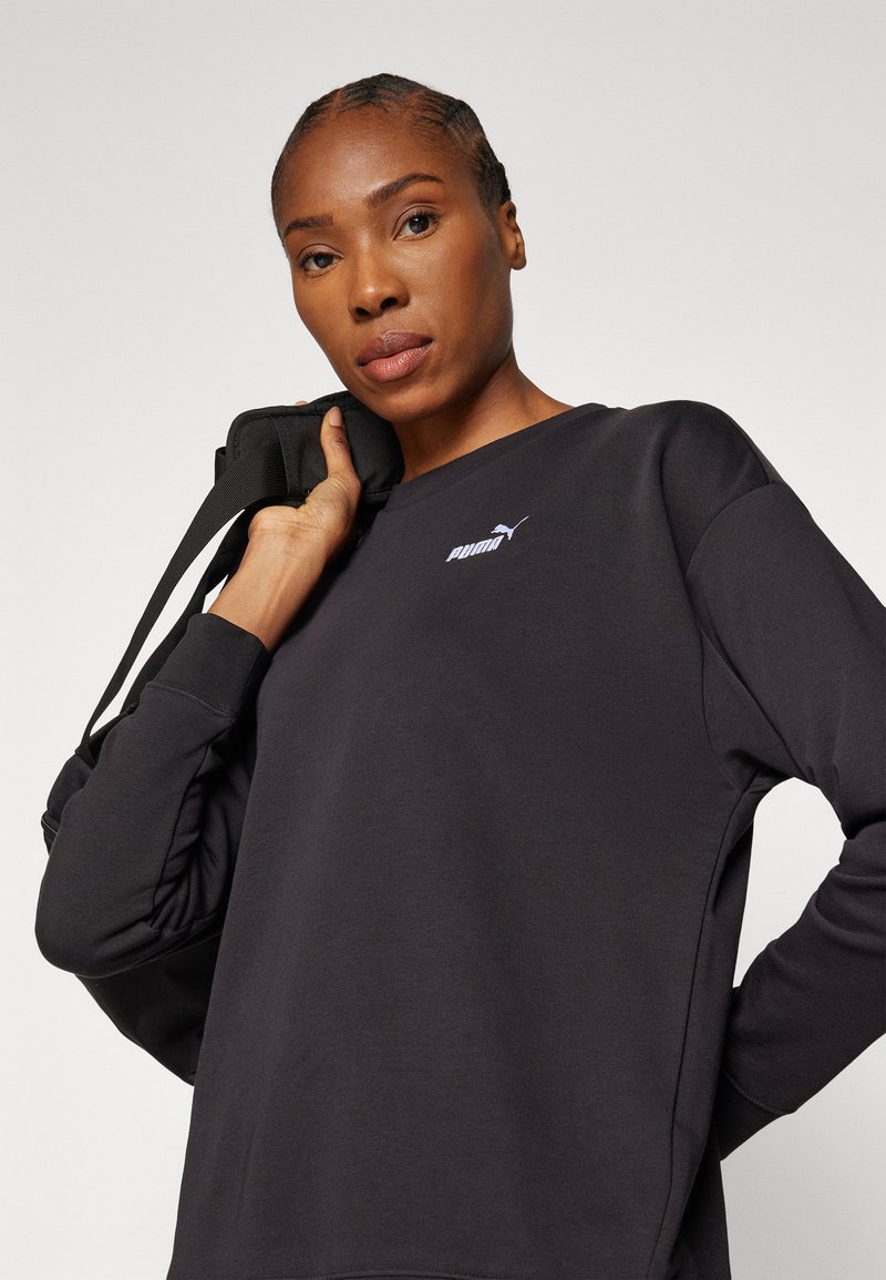 Schwarzer Pullover mit langen Ärmeln und rundem Halsausschnitt, der ein kleines weißes Puma-Logo auf der Brust und einen strukturierten Stoff aufweist.