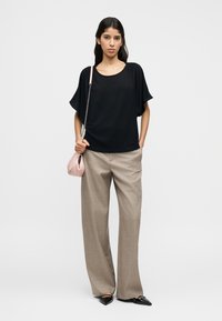 Μαύρο κοντομάνικο τοπ, μπεζ φαρδιά παντελόνια, κρατώντας μια μικρή ροζ τσάντα με αλυσίδα, μαύρα πλατφόρμα μυτερά παπούτσια.