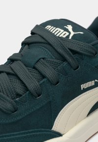 Dark teal sneaker with suede and mesh materials. Features textured laces and white Puma logo, rounded toe, and rubber sole.