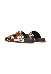 Bruine en witte koeienhuid slide-sandalen met dubbele gouden gespen, donkerbruine zool en open achterkant ontwerp.