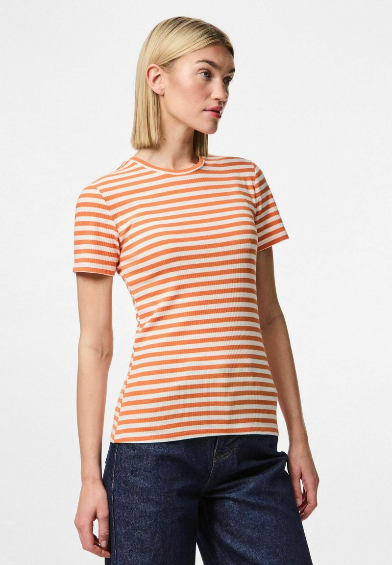 Ribota īsā piedurkņu krekls ar oranžām un baltām horizontālām svītrām. Apaļš kakls un pieguļošs dizains, saskaņots ar tumšiem džinsa biksēm.
