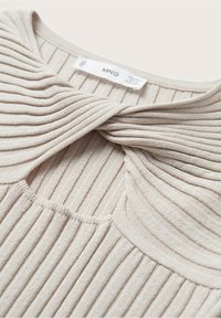 Beżowy sweter prążkowany z okrągłym dekoltem i unikalnym zagięciem na kołnierzu. Miękka faktura z widocznym wzorem dzianiny.