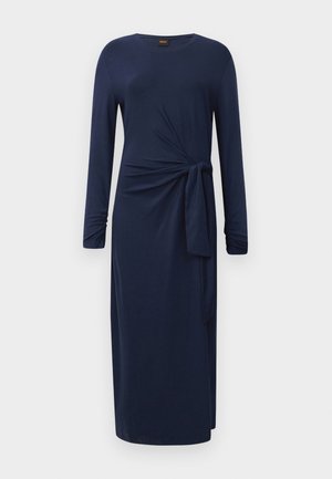 Long-sleeve navy blue midi dress with round neckline, side knot detail, and a straight silhouette against a white background.