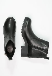 Bottines en cuir noir avec bout arrondi, design à enfiler, fermeture éclair latérale et talon épais cranté pour la stabilité. Texture lisse.