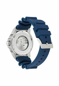 Nautica óra ezüst rozsdamentes acél tokból és kék szilikon szíjból áll, amely texturált felülettel rendelkezik, és kerek óra számlapjával, amelyen látható a mozgás.