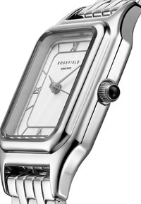 Srebrni pravokutni sat s poliranim metalnim kućištem, bijelim licem s minimalnim oznakama sati i teksturiranim metalnim remenom.