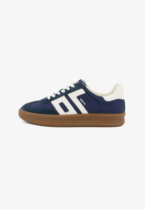 Sneaker blu navy con strisce bianche, tallone bianco, suola in gomma marrone e marchio "BACK 70" su lato e suola.