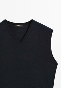Navy sleeveless sweater featuring a V-neckline, fine knit texture, and minimalistic design. Label visible inside the neckline.