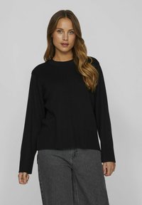 Sweatshirt en tricot noir avec des manches longues, un col rond et une coupe décontractée. Présente un ourlet et des poignets côtelés, une texture lisse et des détails de couture minimaux.