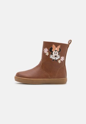 Botte marron mi-mollet à semelle plate avec un visage de Minnie Mouse, un nœud pêche et une broderie de fleurs roses et blanches sur le côté.
