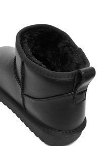 Melni potītes zābaki, izgatavoti no ādas, ar mīkstu melnu mākslīgo kažoku oderi un izturīgu gumijas zoli ar teksturētu saķeri.