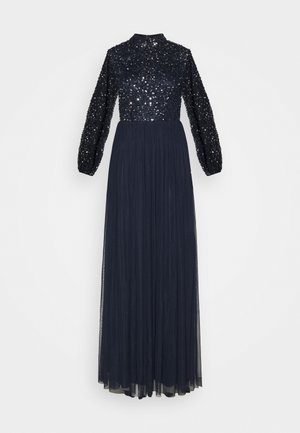 Vestido largo azul marino con un cuerpo de lentejuelas, mangas largas con volumen y una falda plisada fluida, confeccionado en una tela ligera.