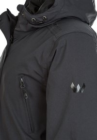 Zwarte geïsoleerde jas met een ritszak, verstelbare capuchon en een gladde textuur. Bevat een reflecterend logo-detail op de schouder.