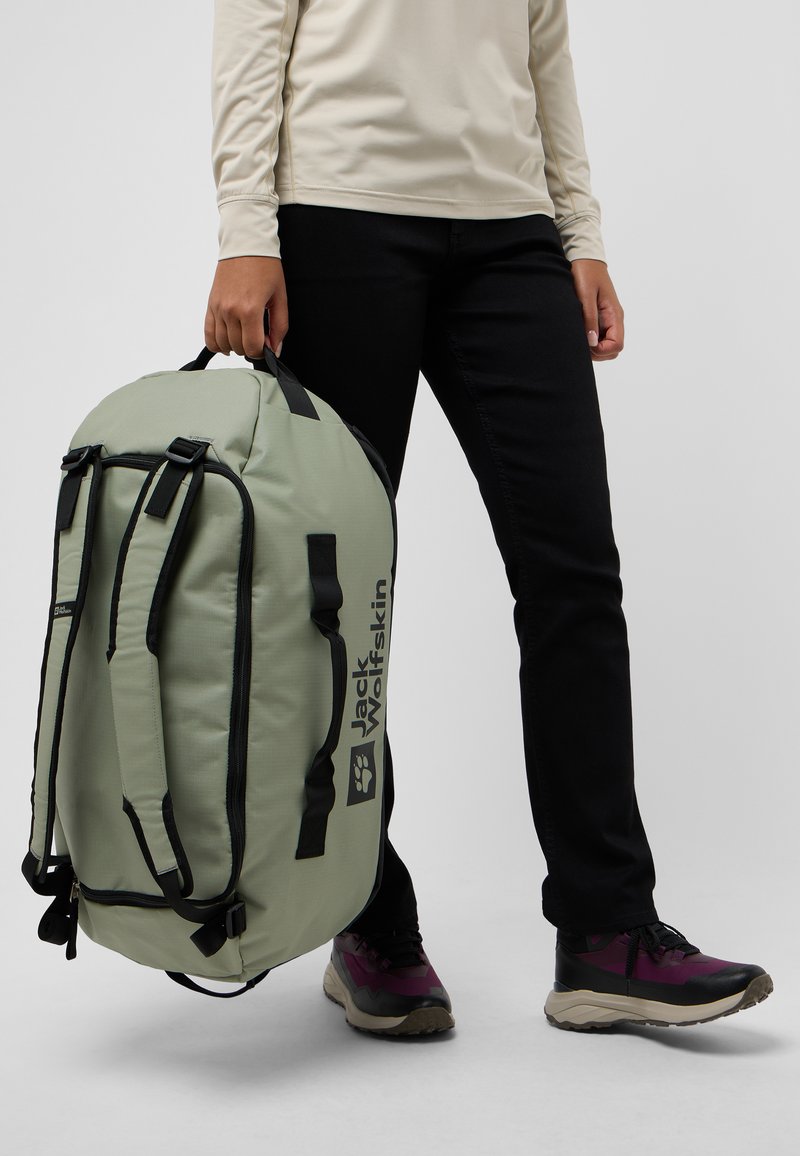 Borsa a tracolla verde chiaro con accenti neri, dotata di spallacci regolabili, un compartimento principale con zip e un logo ben visibile.
