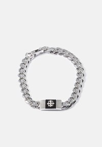 Bracciale in argento con maglie spesse, caratterizzato da una piastrina decorativa rettangolare in nero e argento con un piccolo emblema a forma di fiore.