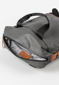 Grijze synthetische rugzak met bruine leren accenten, ontworpen met een bovenste rits en een interieurvoering met een rasterpatroon. Twee stoffen handvaten.