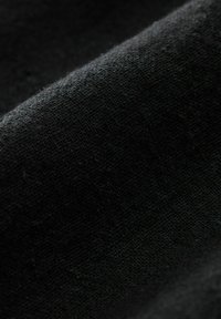 Tejido negro con una textura suave, que presenta un tejido fino. La superficie muestra variaciones sutiles y un ligero brillo.