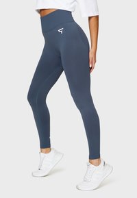 Hochtaillierte, blickdichte marineblaue Leggings mit einer glatten Textur, die ein kleines Logo am Bund und kontrastierende Nähte aufweisen.