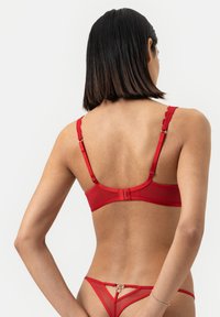 Rode bh met kantafwerking, verstelbare bandjes, haaksluiting en doorschijnend materiaal, gecombineerd met een bijpassende rode string met een dubbele lusaccent.