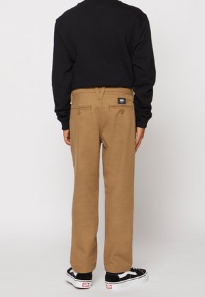 Brune cargobukser med afslappet pasform, der har baglommer og en mærkat i taljen, kombineret med sorte sko og en sort langærmet skjorte.